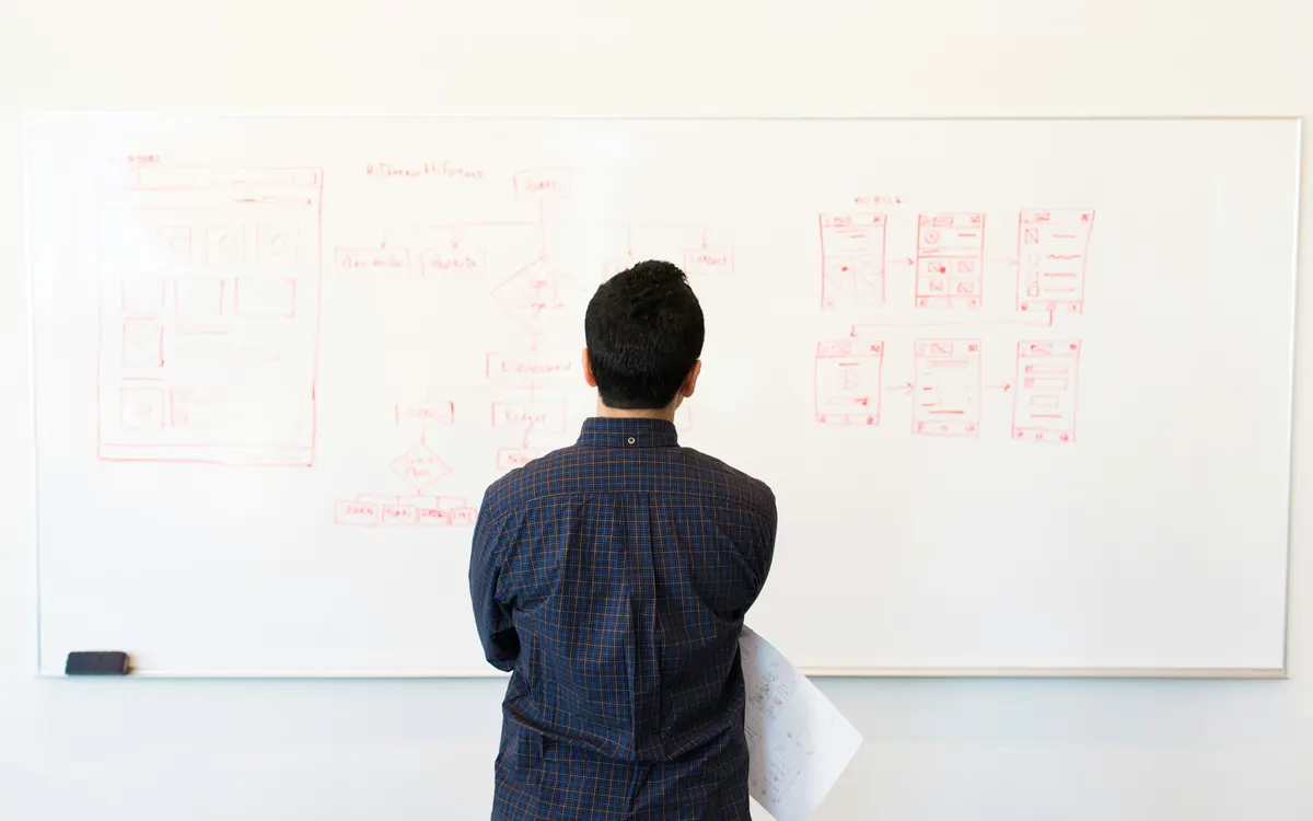 Ingeniero frente a una pizarra con diagramas de arquitectura